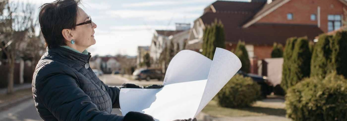 Property owner reviewing building plans on a residential street before starting a new home build