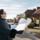 Property owner reviewing building plans on a residential street before starting a new home build