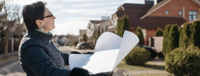 Property owner reviewing building plans on a residential street before starting a new home build