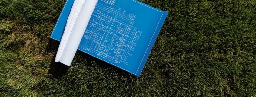 Building plans laid on grass for a property survey and site development assessment